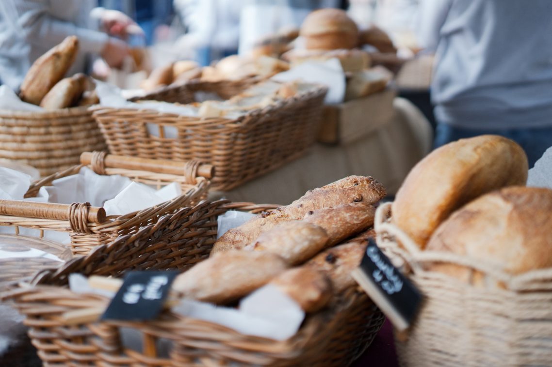 Baskets of various freshly baked breads on display at a market stall.