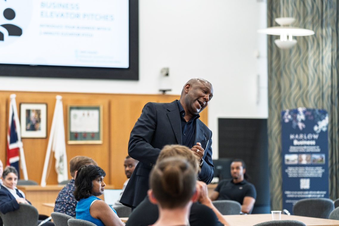 A speaker engages an audience in a conference room setting.