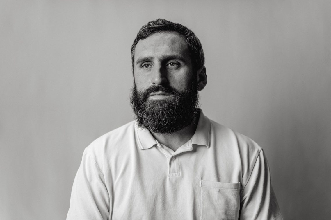 Black and white portrait of a man with a beard, wearing a polo shirt, looking calmly forward.